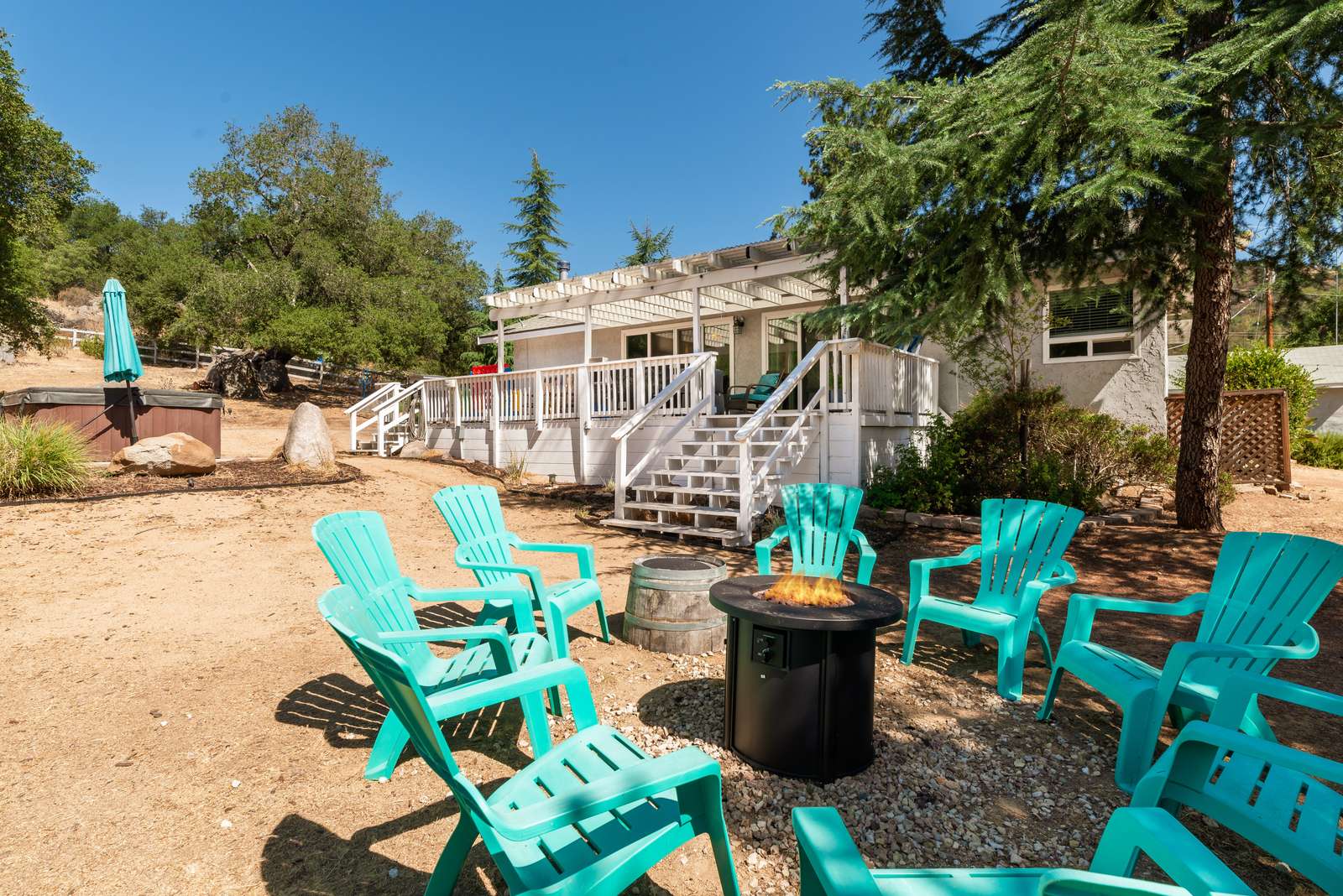 The fire pit lit at the foot of the deck, ringed by turquoise Adirondack chairs, with the hot tub off to one side.