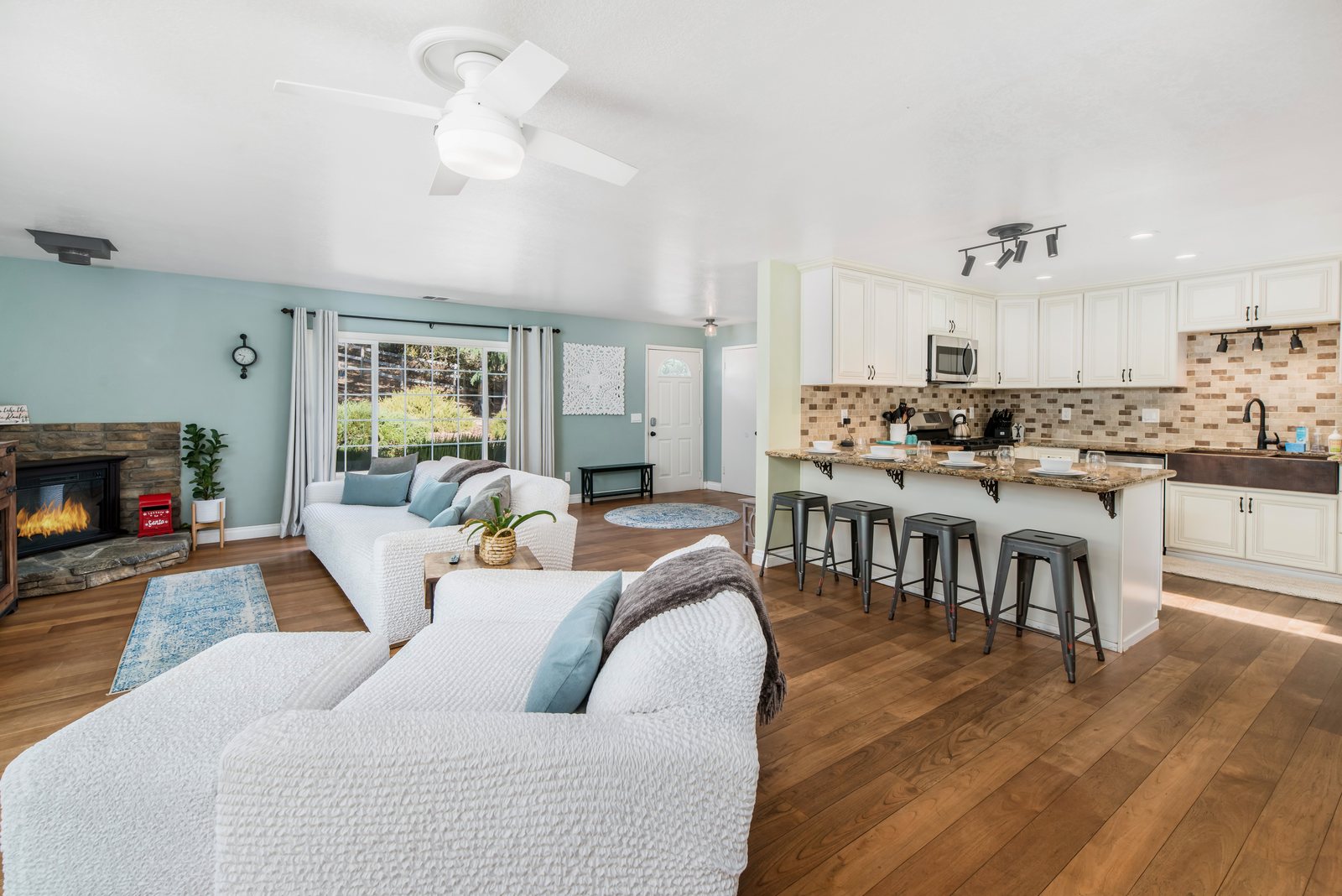 The open living room and kitchen: a stone fireplace, two long sofas and a granite breakfast bar with six stools.