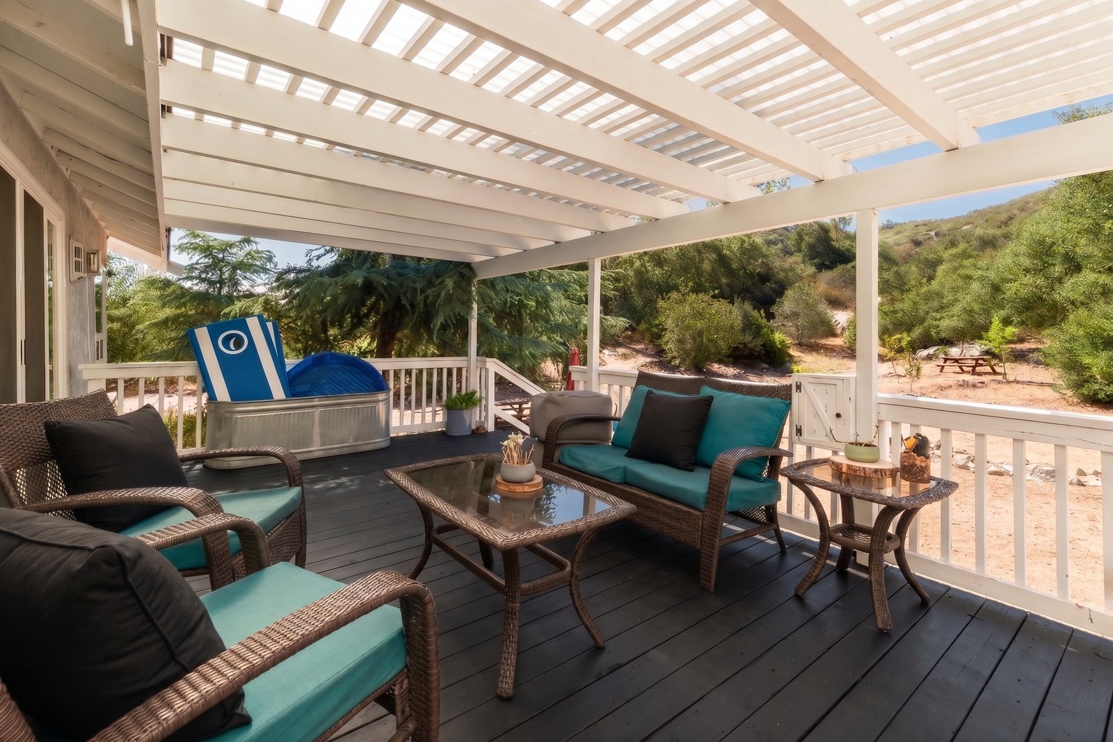 The covered deck under the white pergola, with cushioned seating looking out over the hillside.