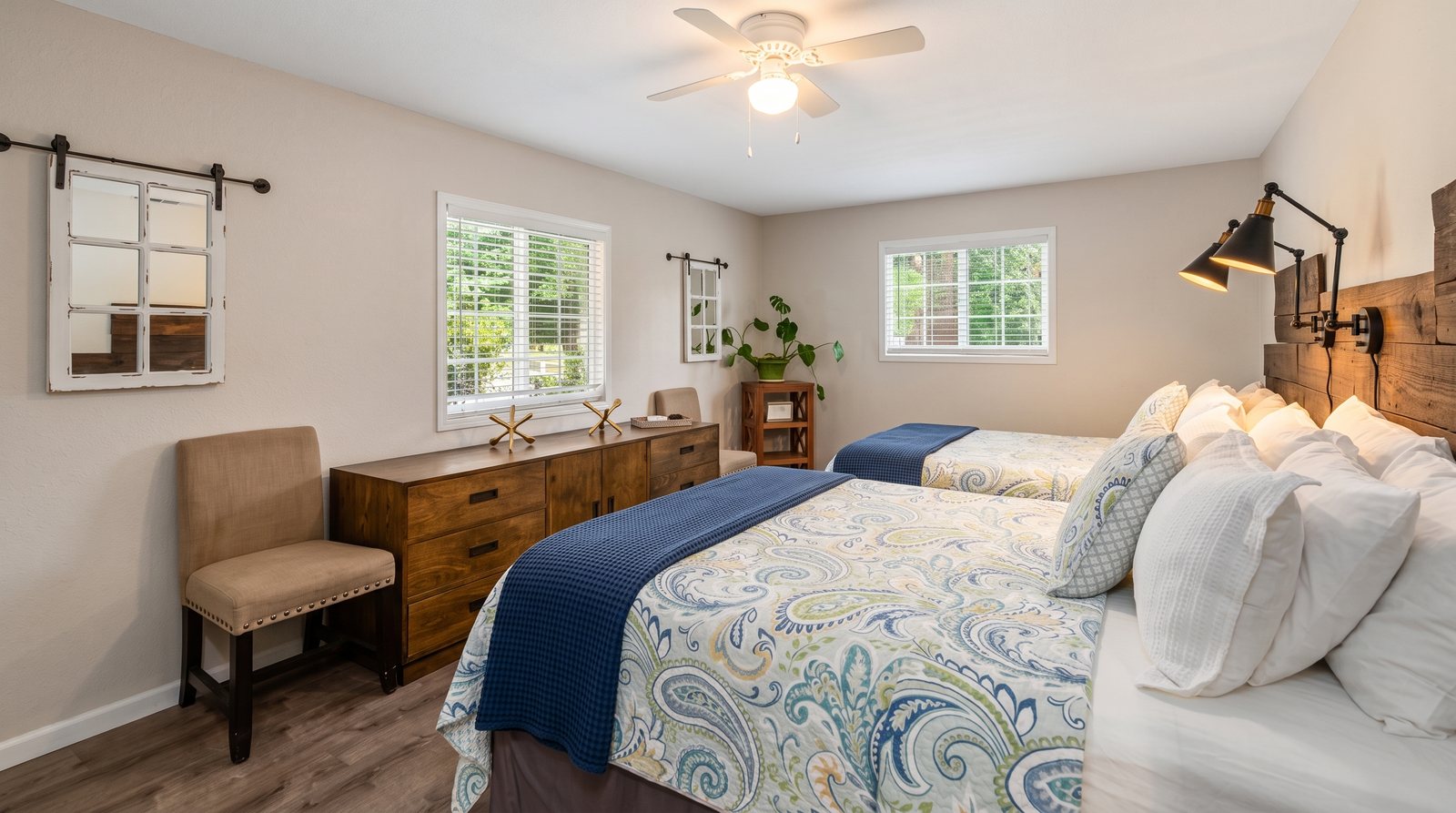 A bedroom with two queen beds made up in navy and white.