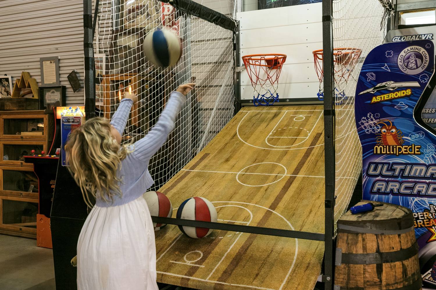 A girl shooting at the arcade basketball machine in the game barn.