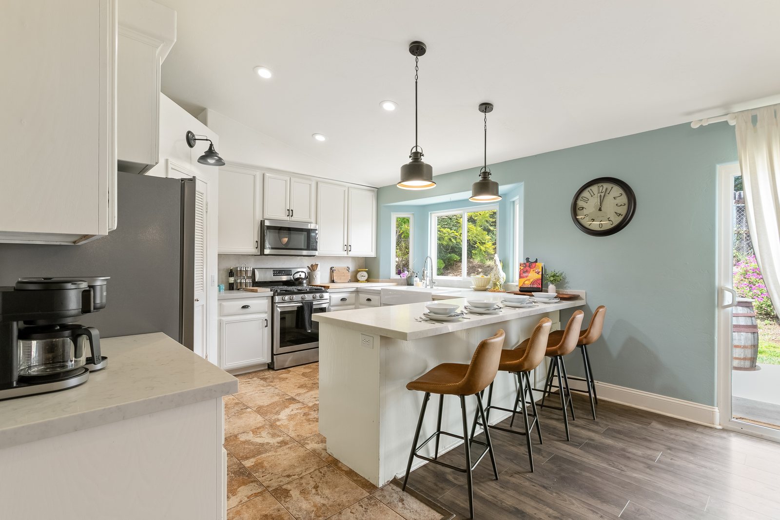 The kitchen bar seating with pendant lights and a window over the sink.