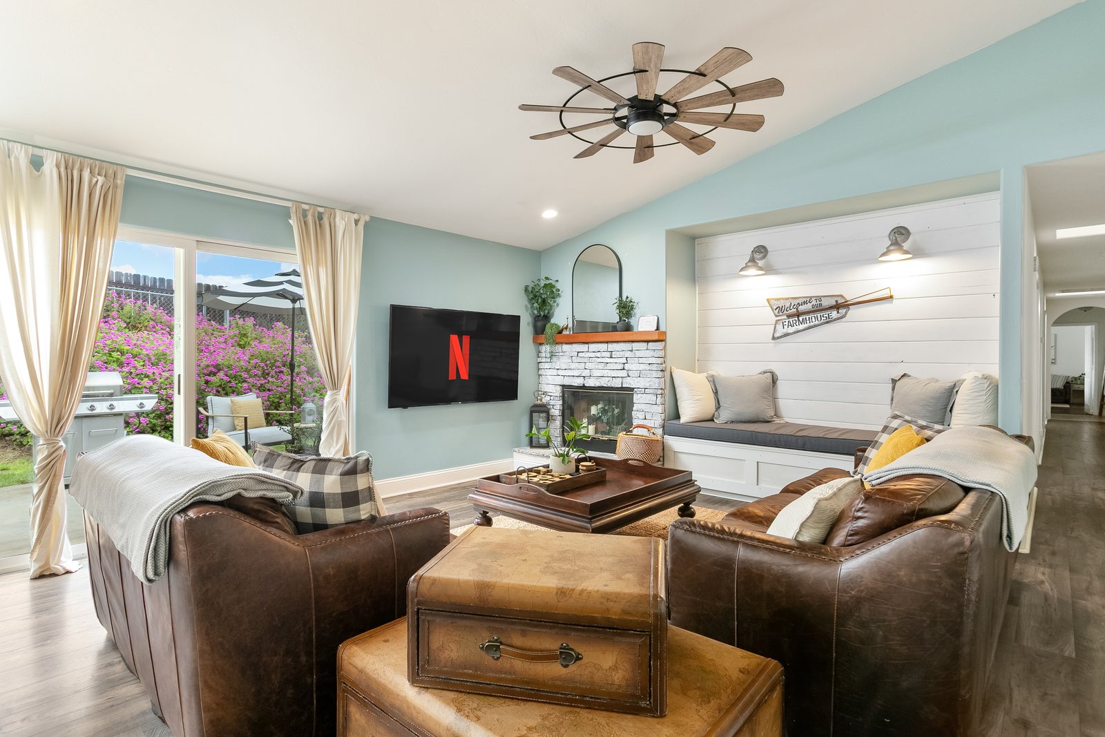 Living room at Red Barn Ranch with leather sofas, a stone fireplace and a shiplap window seat.