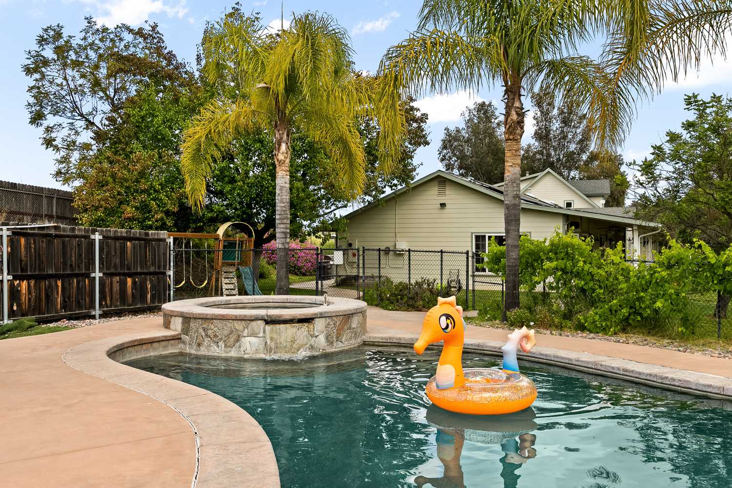 The spa spilling into the pool, with palms and the ranch house behind.