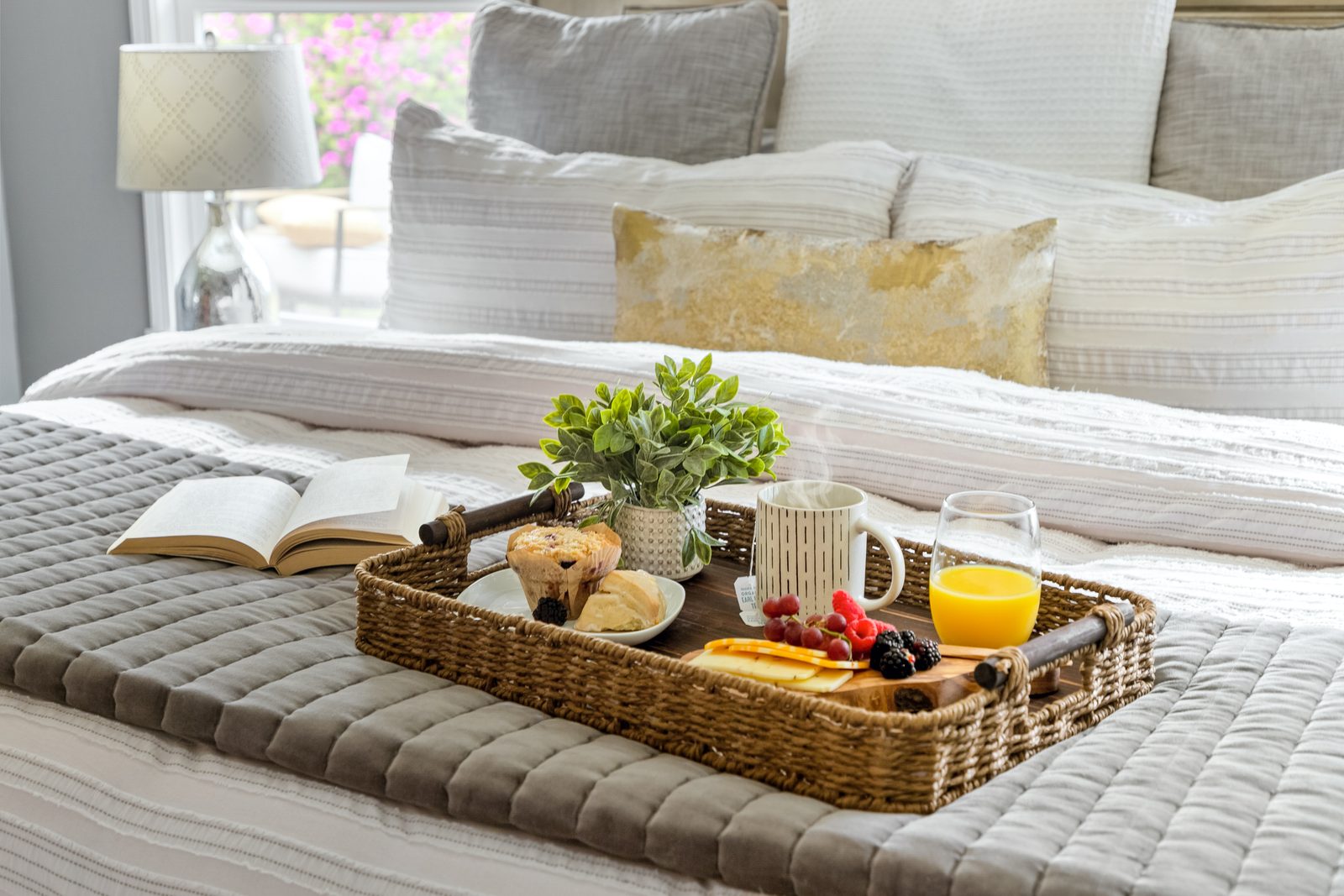 A breakfast tray on the bed in the Primary, with coffee, juice and a book.
