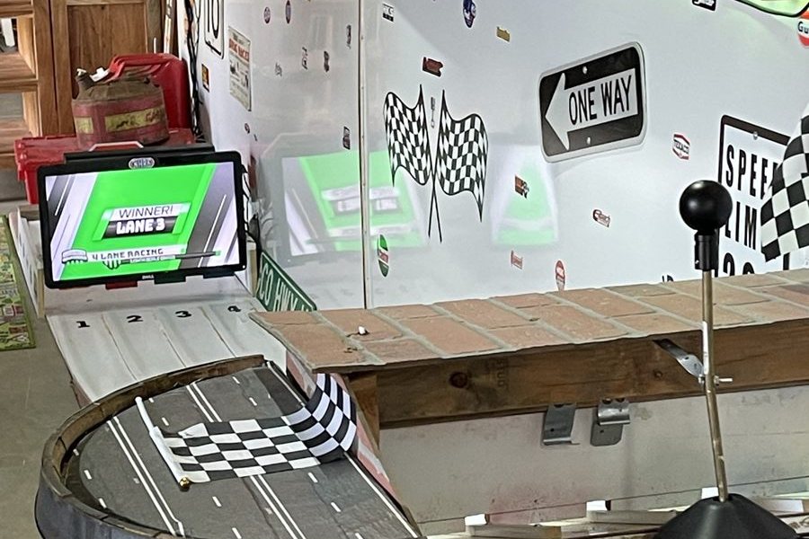 The four lanes of Legend’s Dragway with the winner screen lit and a checkered flag on the barrel.