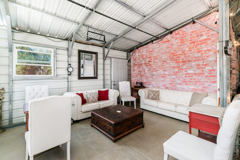 White tufted sofas around a wooden chest by the brick wall.